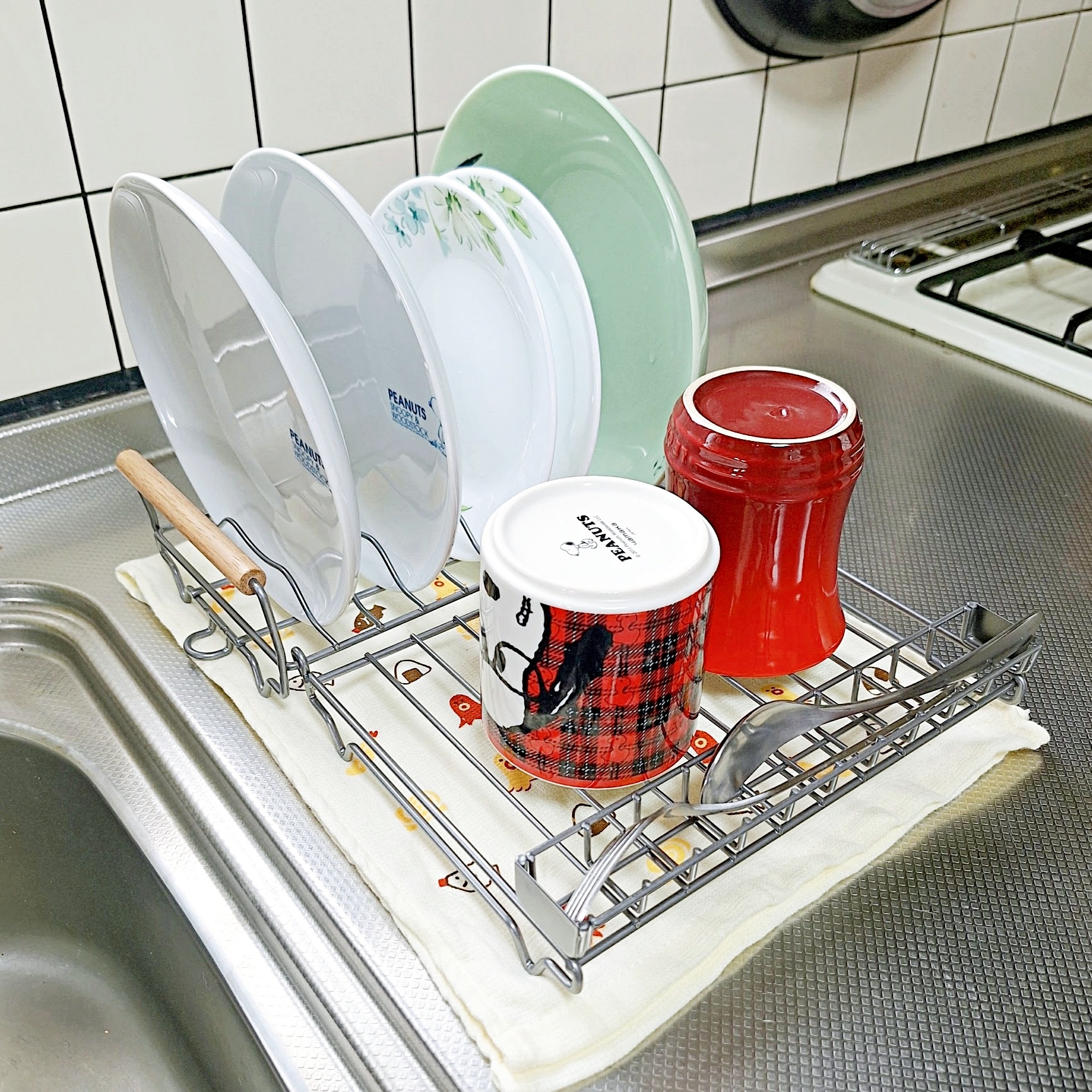 乾いた皿やカップがシンクの横の水切りラックに並べられている様子。