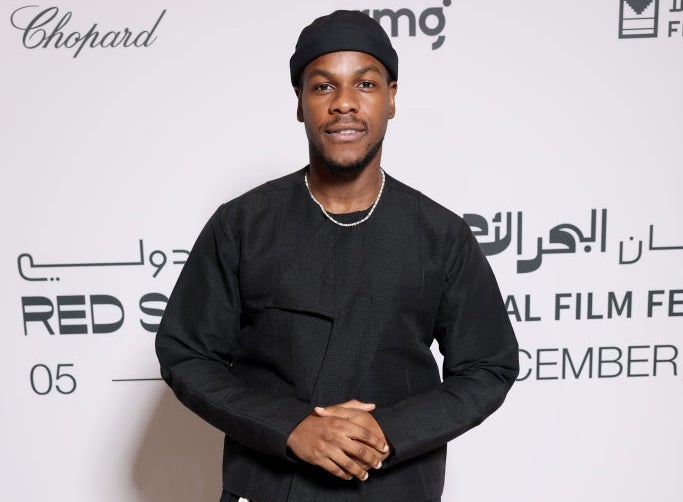 Actor in a black outfit and white sneakers on the red carpet at a film festival
