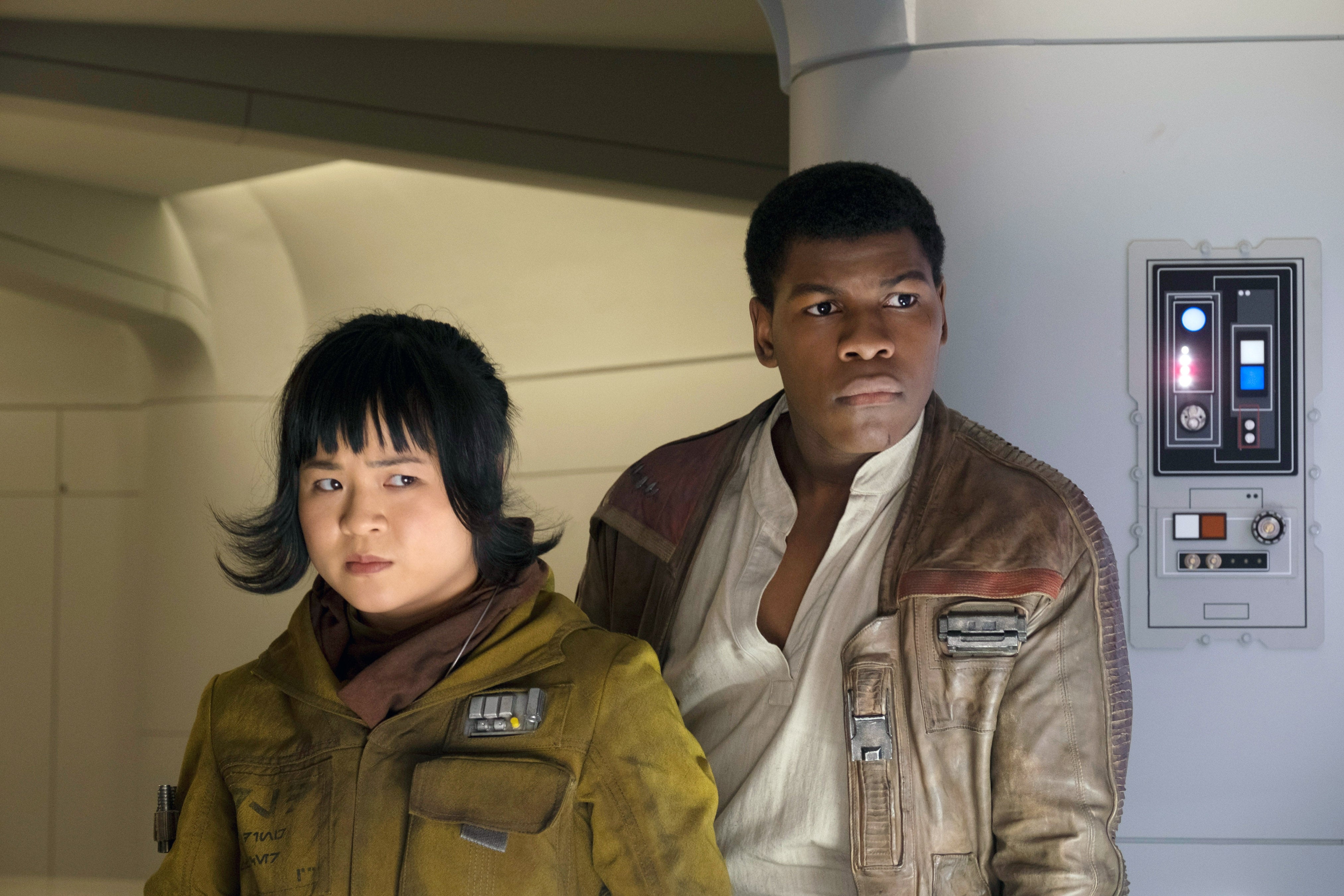 Two characters stand in a sci-fi setting, dressed in futuristic, rugged outfits, looking intently off-camera