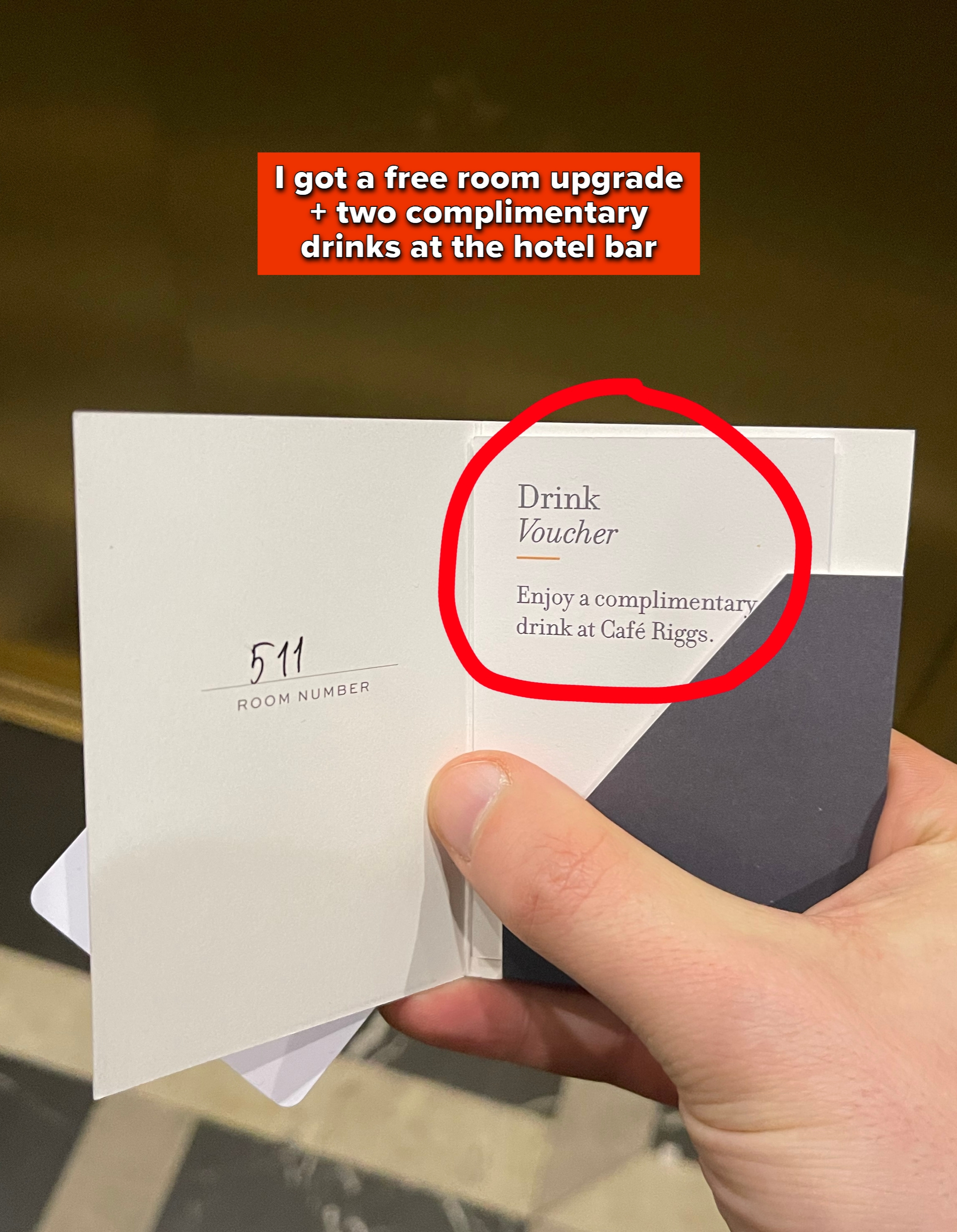 Hand holding a drink voucher for a complimentary beverage at Café Riggs, with room number 511 noted
