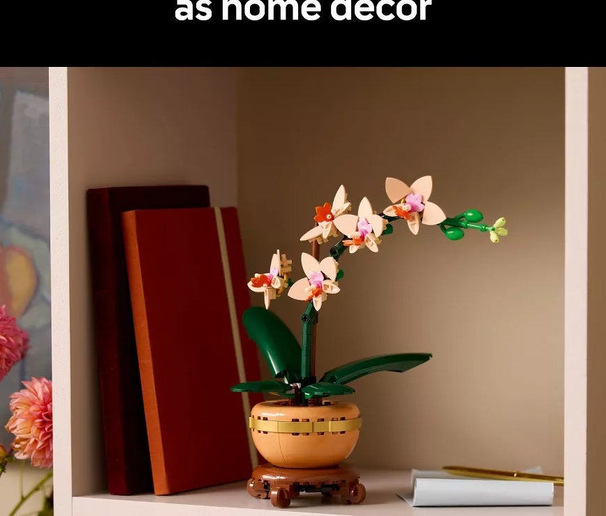 LEGO orchid set displayed on a shelf with books and a notebook, styled as home decor