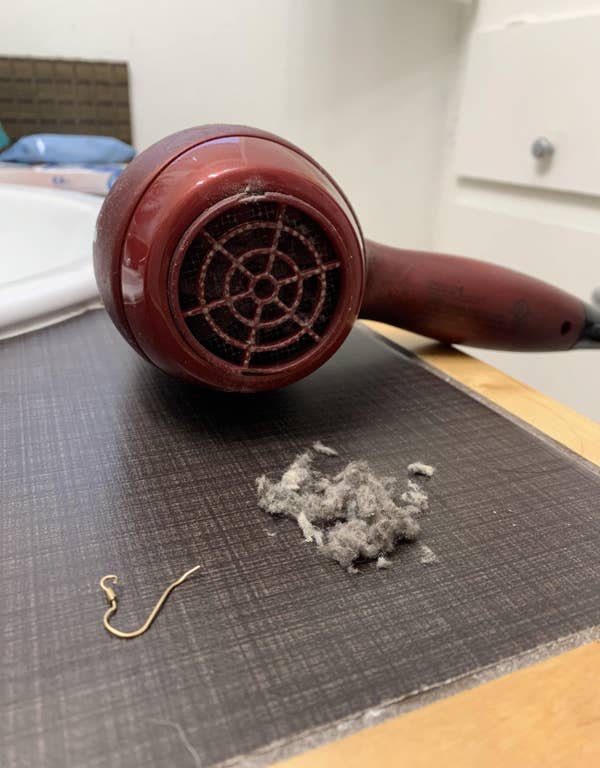 Hair dryer with lint on a table; Reddit post advises cleaning the back of your hair dryer