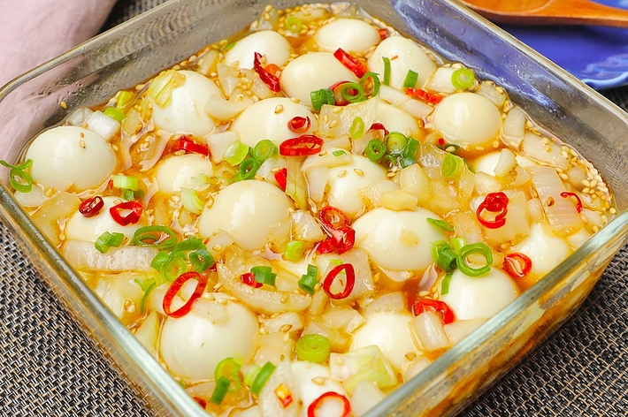 たくさんのウズラの卵が入ったスパイシーな料理。刻んだネギと唐辛子がトッピングされています。