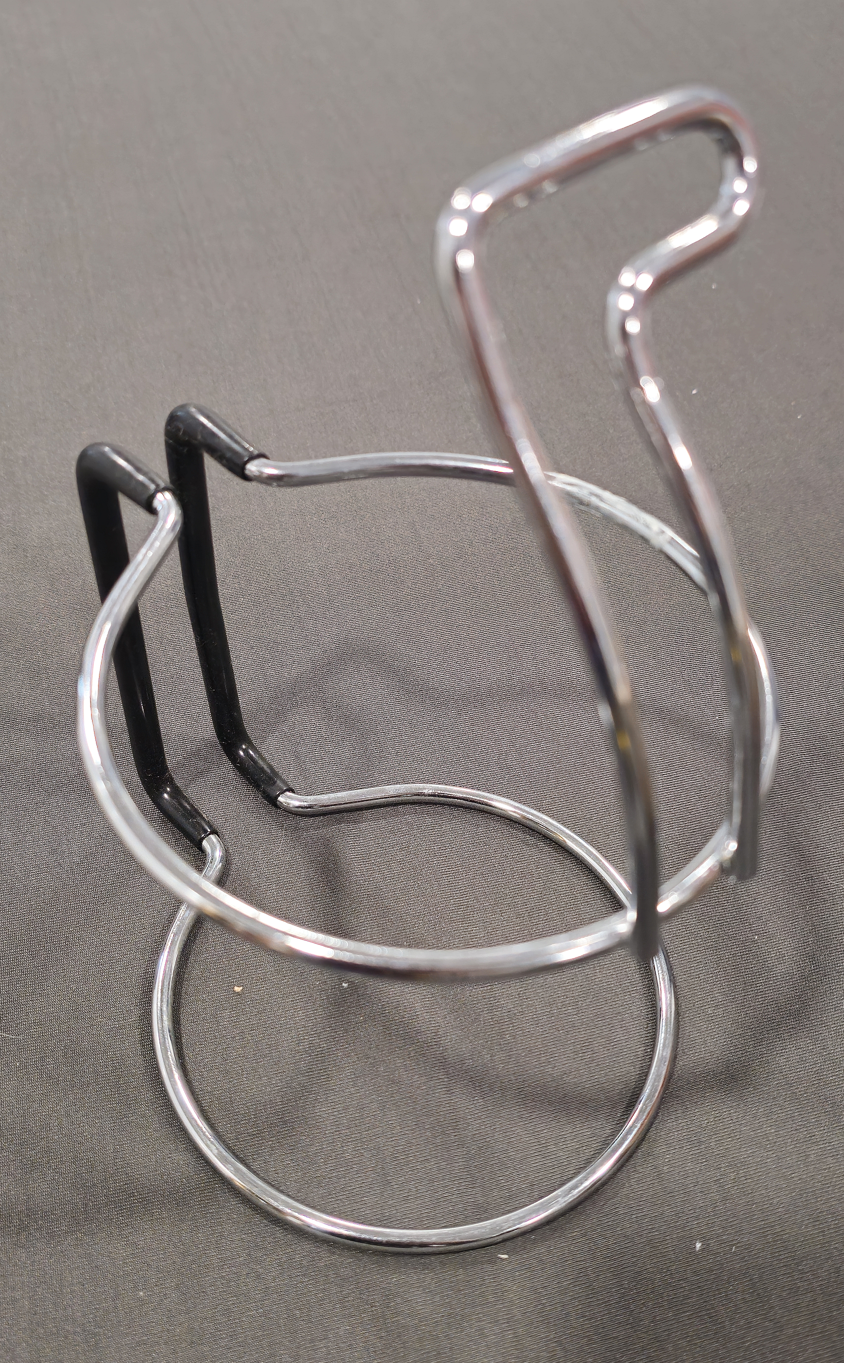 Metal wire holder for a restaurant, often used for holding condiment bottles or napkins, on a plain background