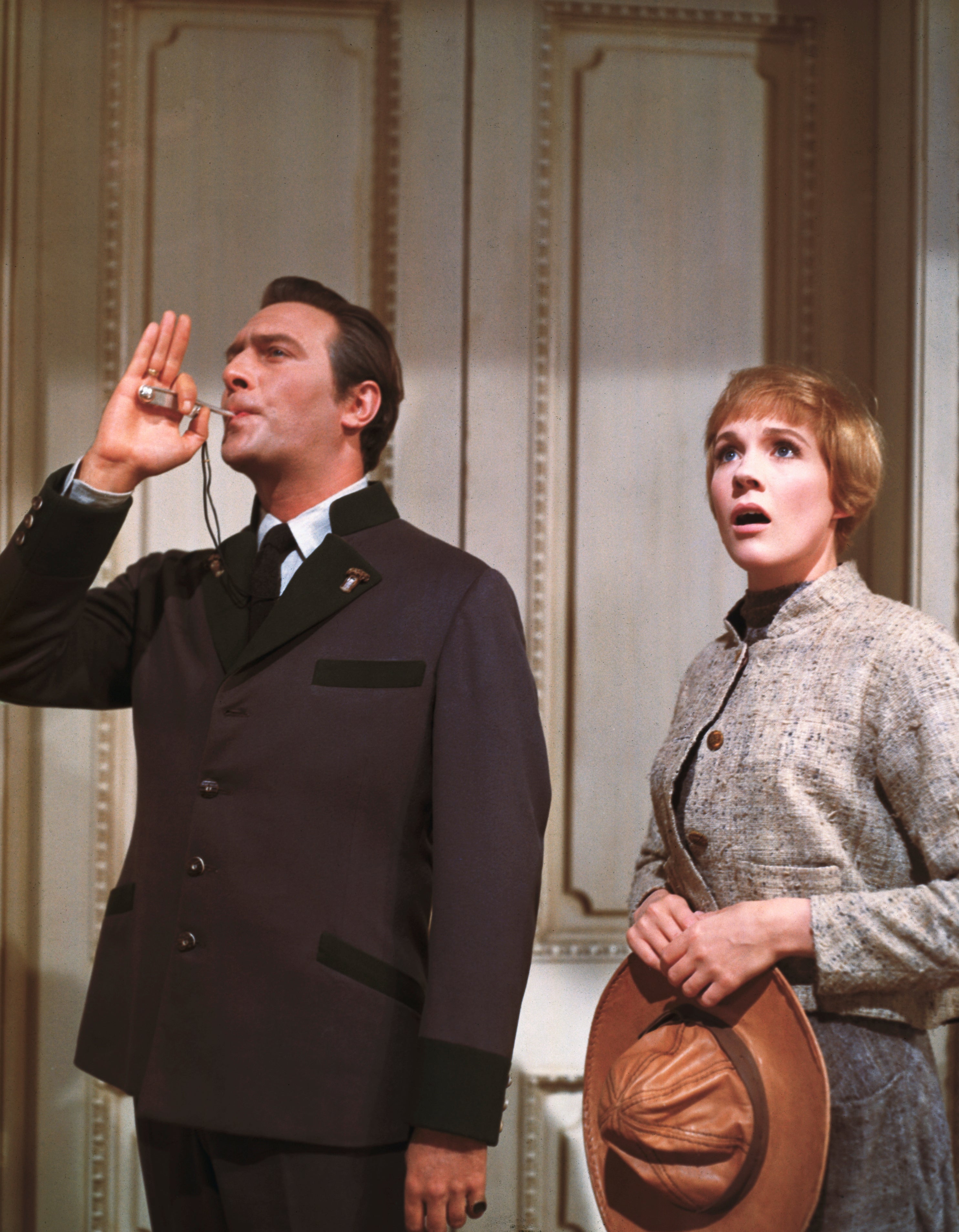 A scene from a classic film with a man in a formal suit blowing a whistle and a surprised woman in a vintage outfit holding a hat