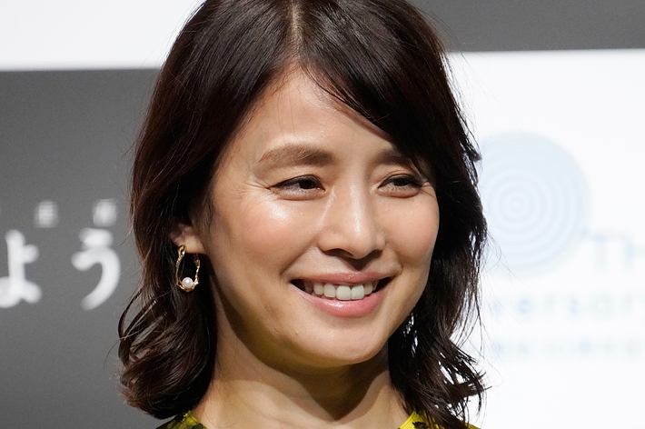 俳優が花柄のドレスを着て微笑んでいる。