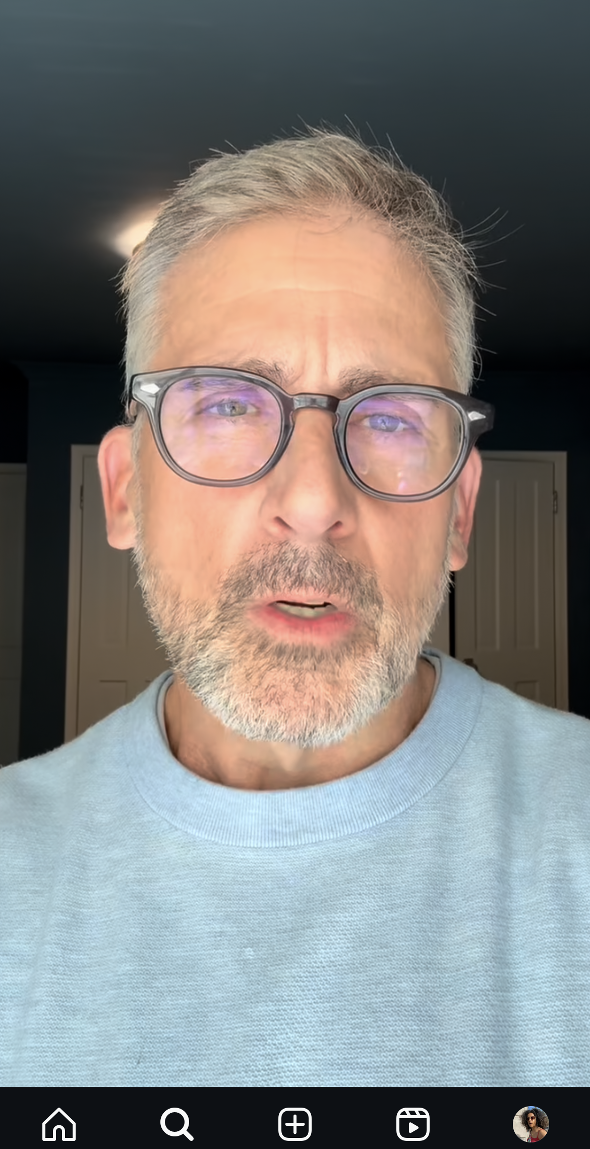 Mann med briller og skjegg iført en lett genser ser direkte på kameraet i en selfie