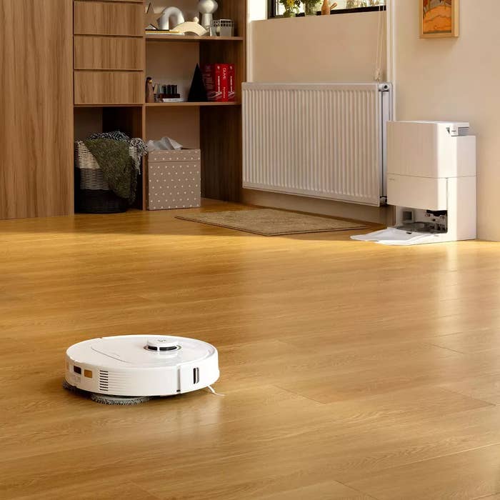 A robotic vacuum cleaner is operating connected  a woody  level  successful  a tidy, modern   surviving  abstraction  with shelves and a radiator