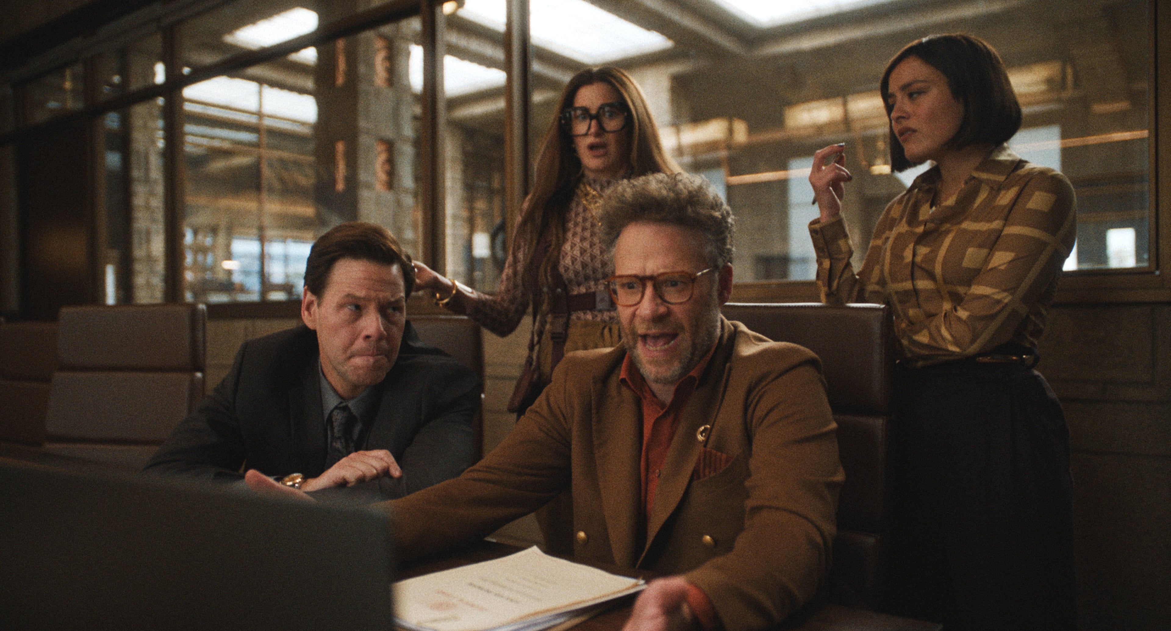 Seth Rogen, Ike Barinholtz, and Kathryn Hahn in a scene from "The Studio" where they sit in a conference room appearing surprised
