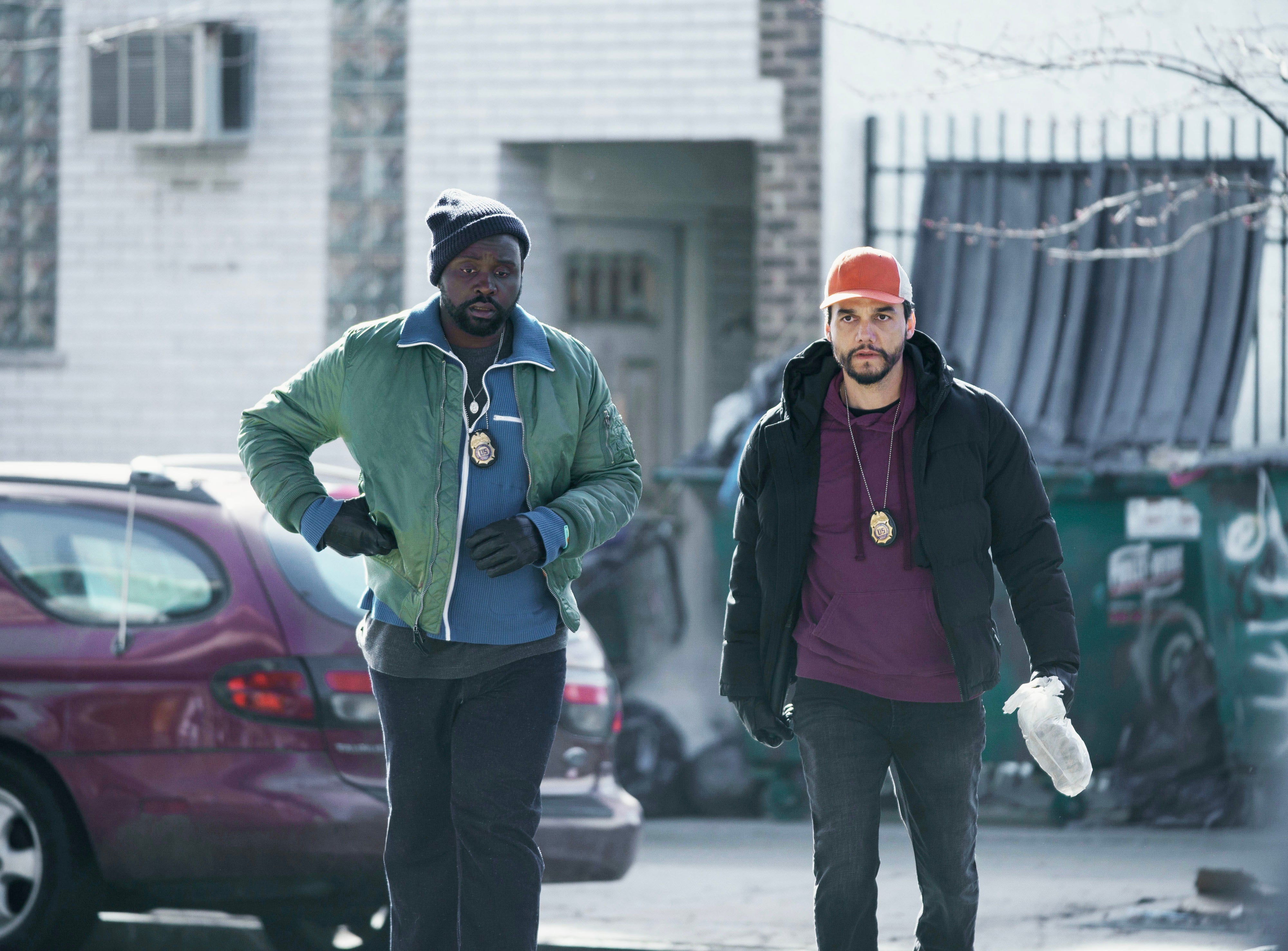 Two characters in casual outfits with badges walk purposefully on a street