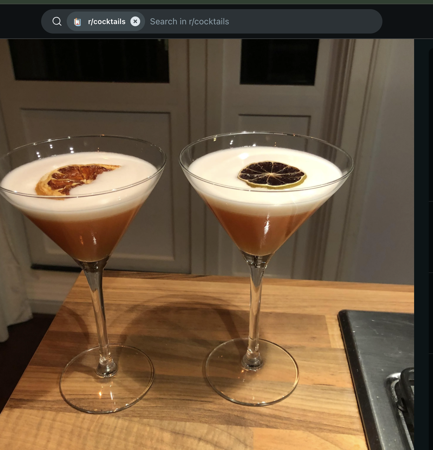 To cocktailglass på et trebord, hver fylt med en skummende drink pyntet med en tørket sitrusskive