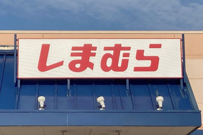Storefront with a sign in Japanese script over an entrance, featuring a visible accessible parking sign in the corner