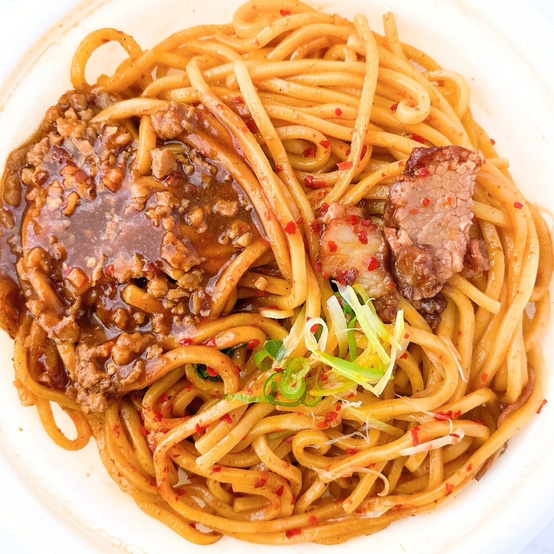 ボウルに入った麺料理。ミートソースと刻んだ青ねぎがトッピングされています。