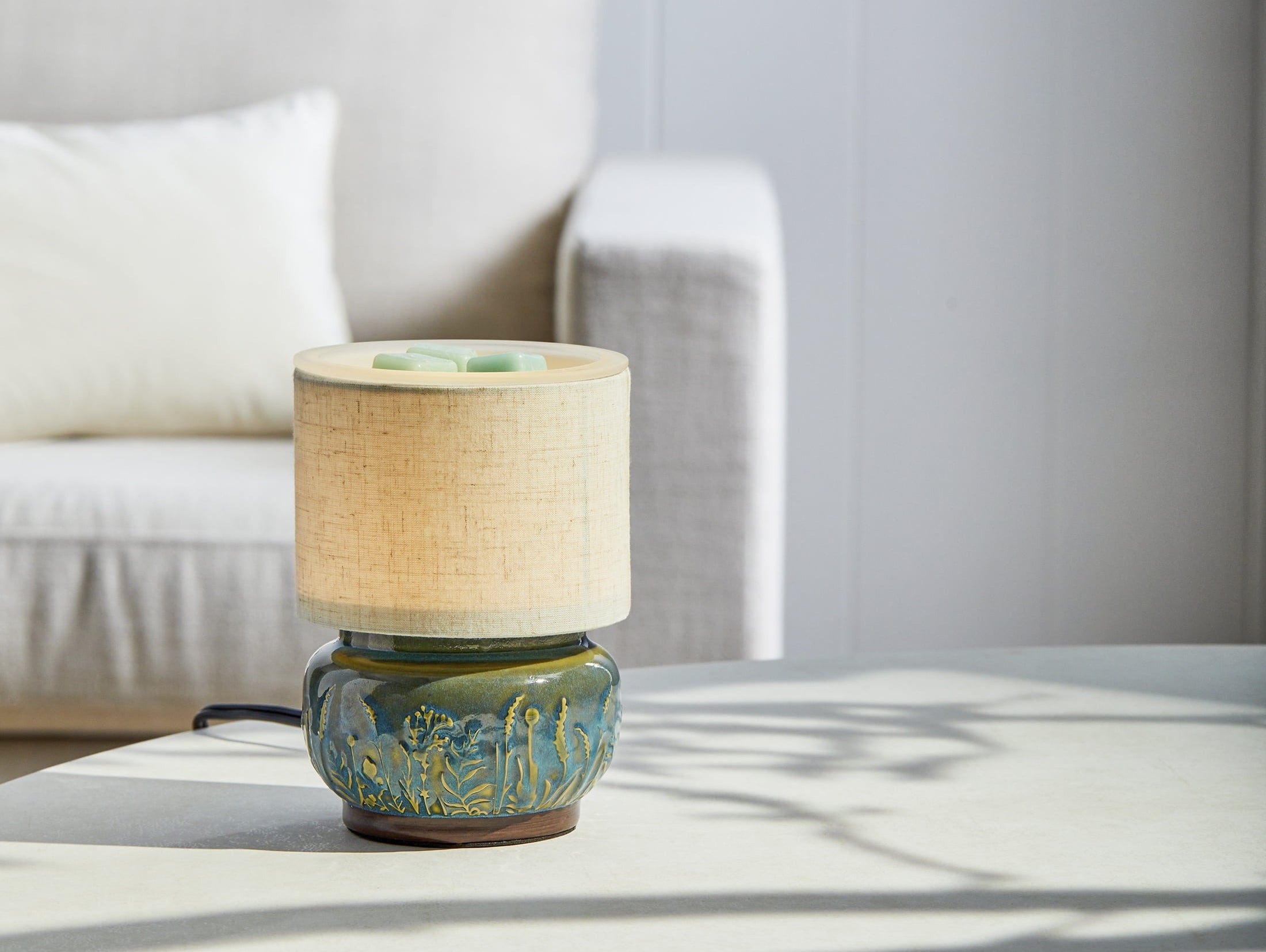 Mini ceramic table lamp with a textured base and a fabric shade on a round table