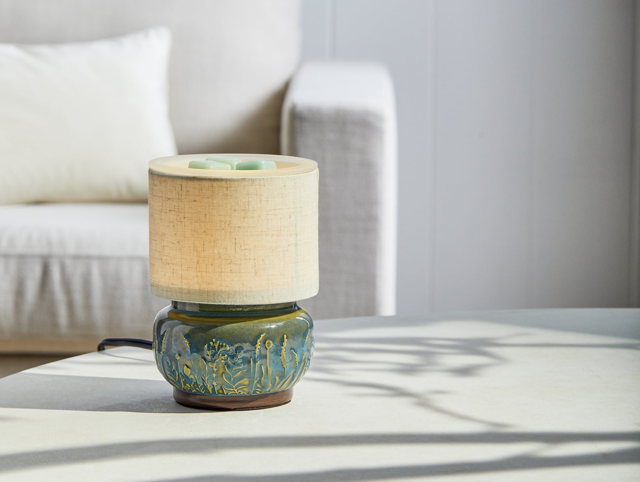 Mini ceramic table lamp with a textured base and a fabric shade on a round table