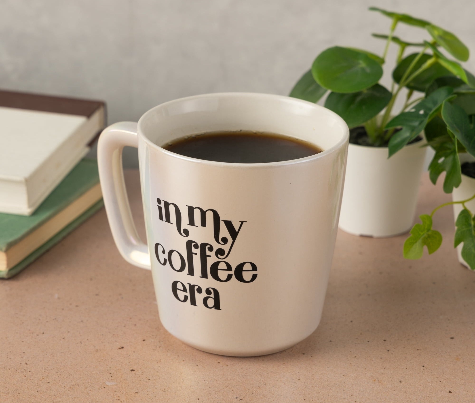 A white coffee mug on a table with the phrase "in my coffee era" printed on its side
