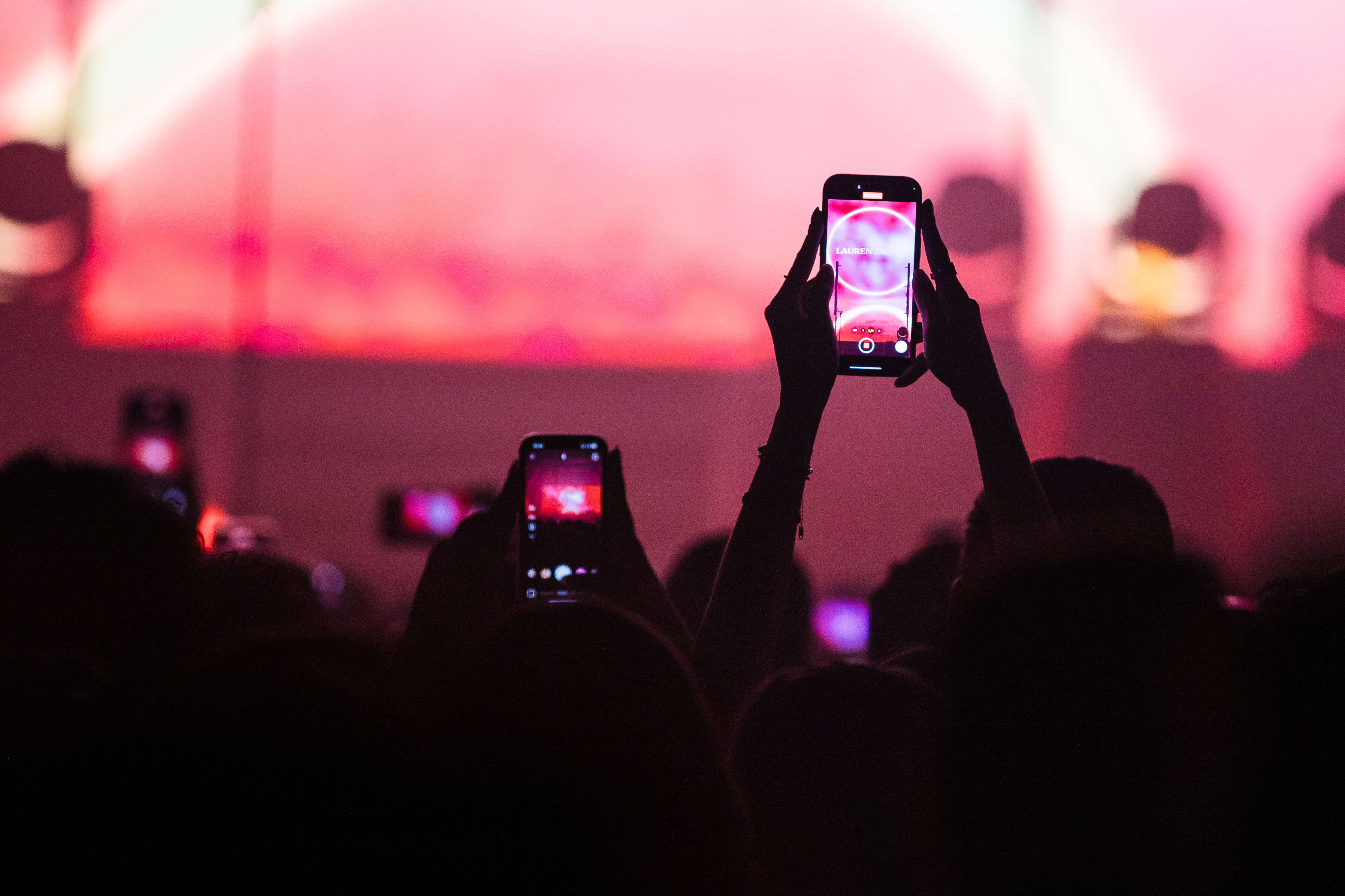 People holding up smartphones at a concert, capturing the performance