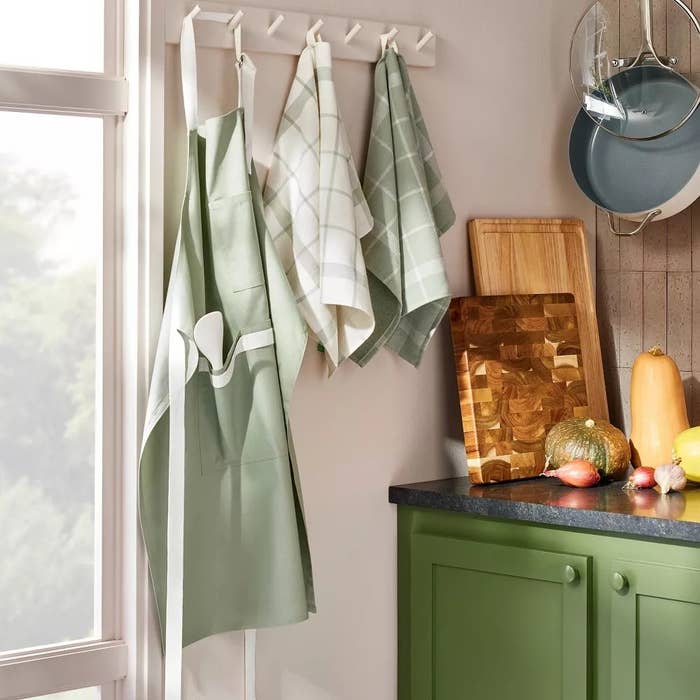 Kitchen with hanging aprons and towels, color-coordinated with greenish  cabinets. Cutting committee  and nutrient   connected  the counter