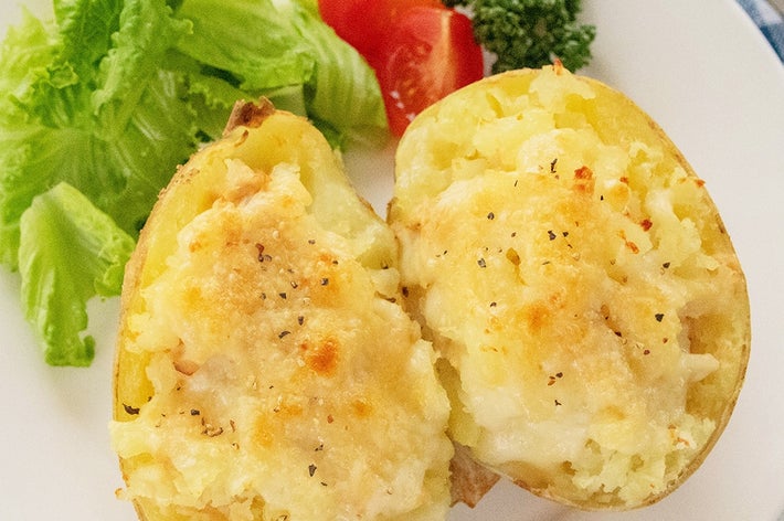 皿に盛られたツナとチーズの焼きポテト、レタスとトマトが添えられている。