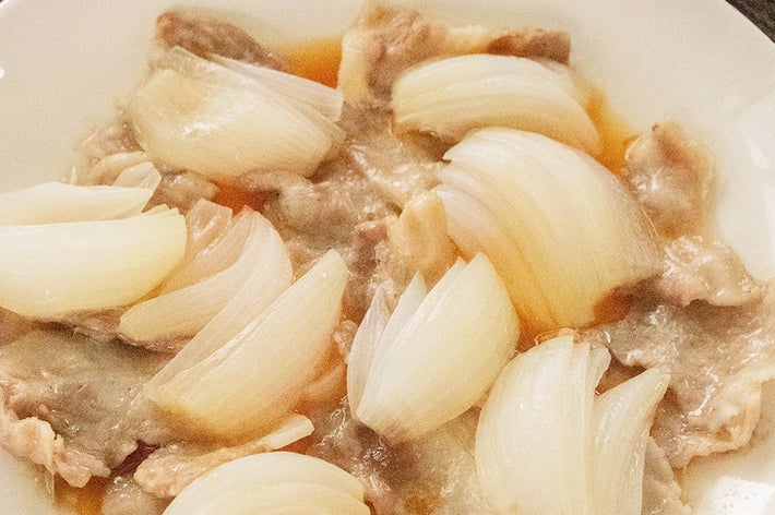 新玉ねぎと豚バラ肉のレンジ蒸しが白い皿に盛られている。