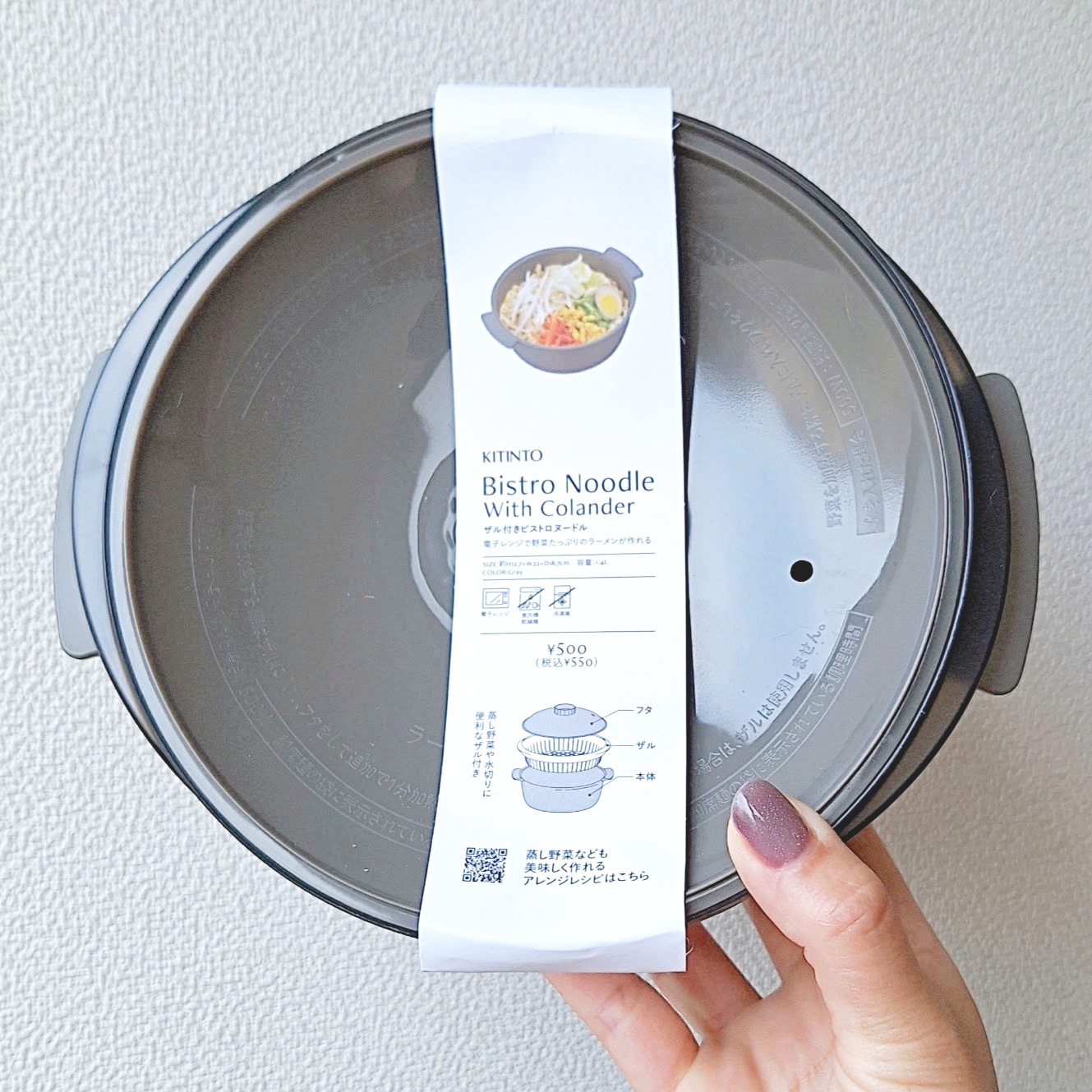 手に持った円形の容器に「ビストロヌードルウィズコランダー」の説明文が添付されています。