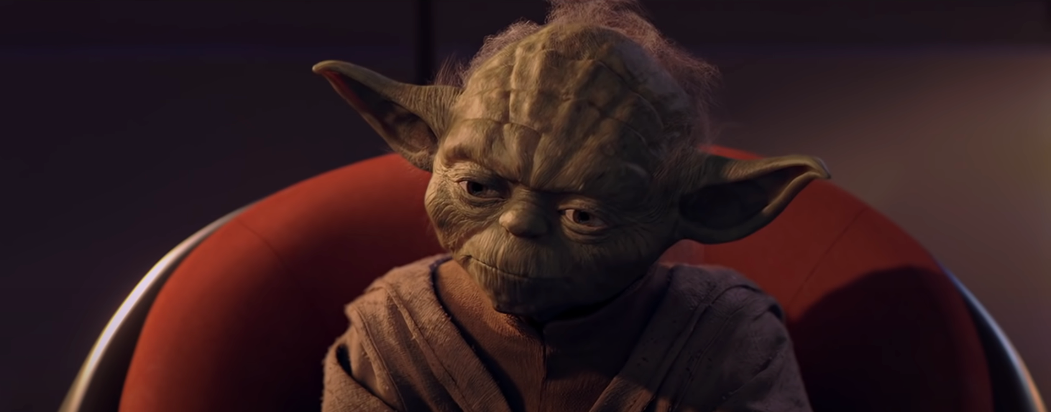 Yoda sits on a red chair, staring pensively into the distance