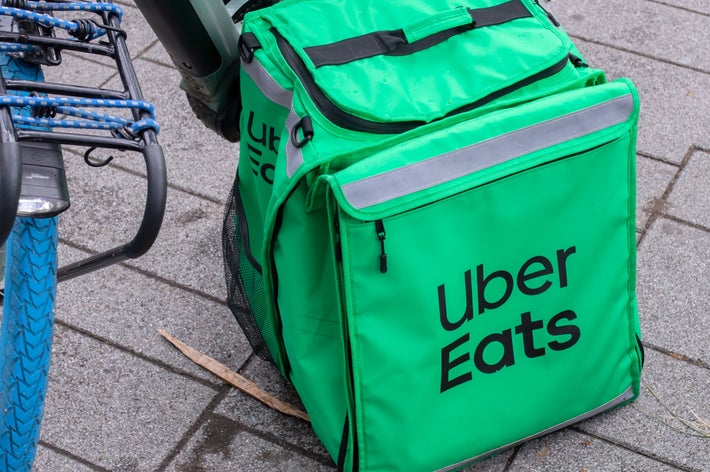 自転車のそばに置かれたUber Eatsの配達用バッグ。