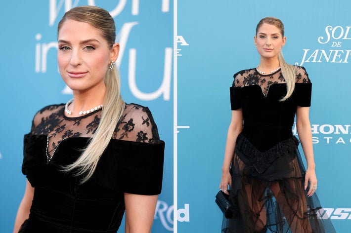 Person wearing a sheer black lace gown with pearl details on a red carpet