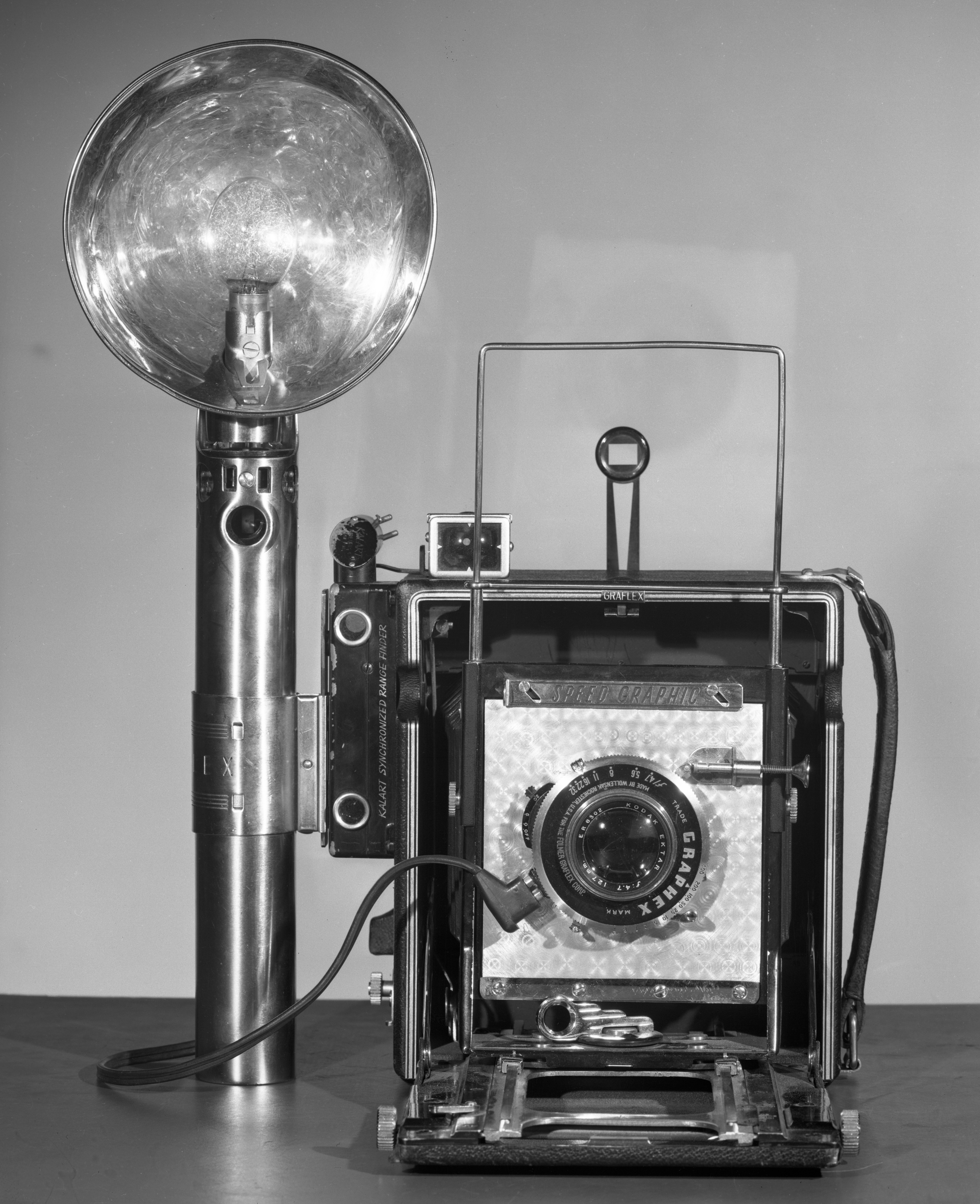 Vintage camera with large flash attachment displayed against a neutral background