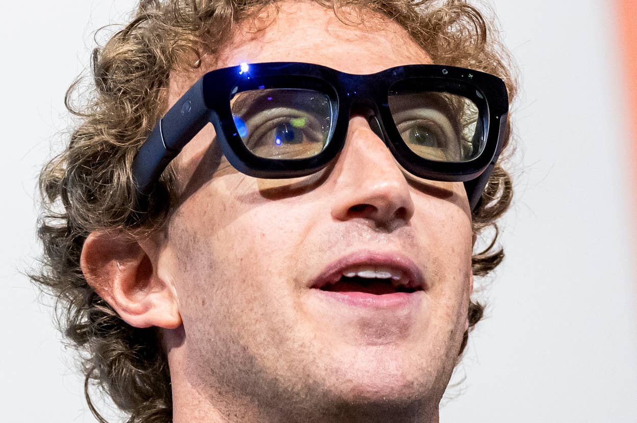 A person wearing large, modern tech glasses with a surprised expression at a tech event