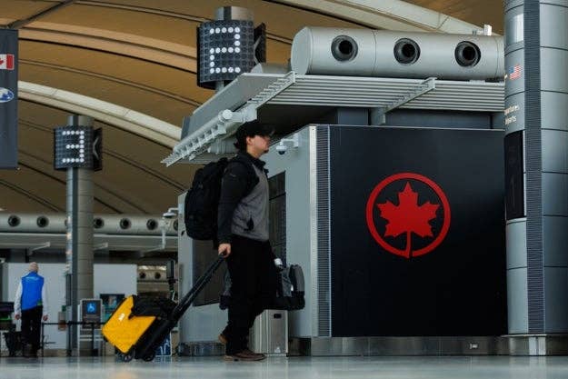 Person pulling luggage in airport terminal with Air Canada logo visible