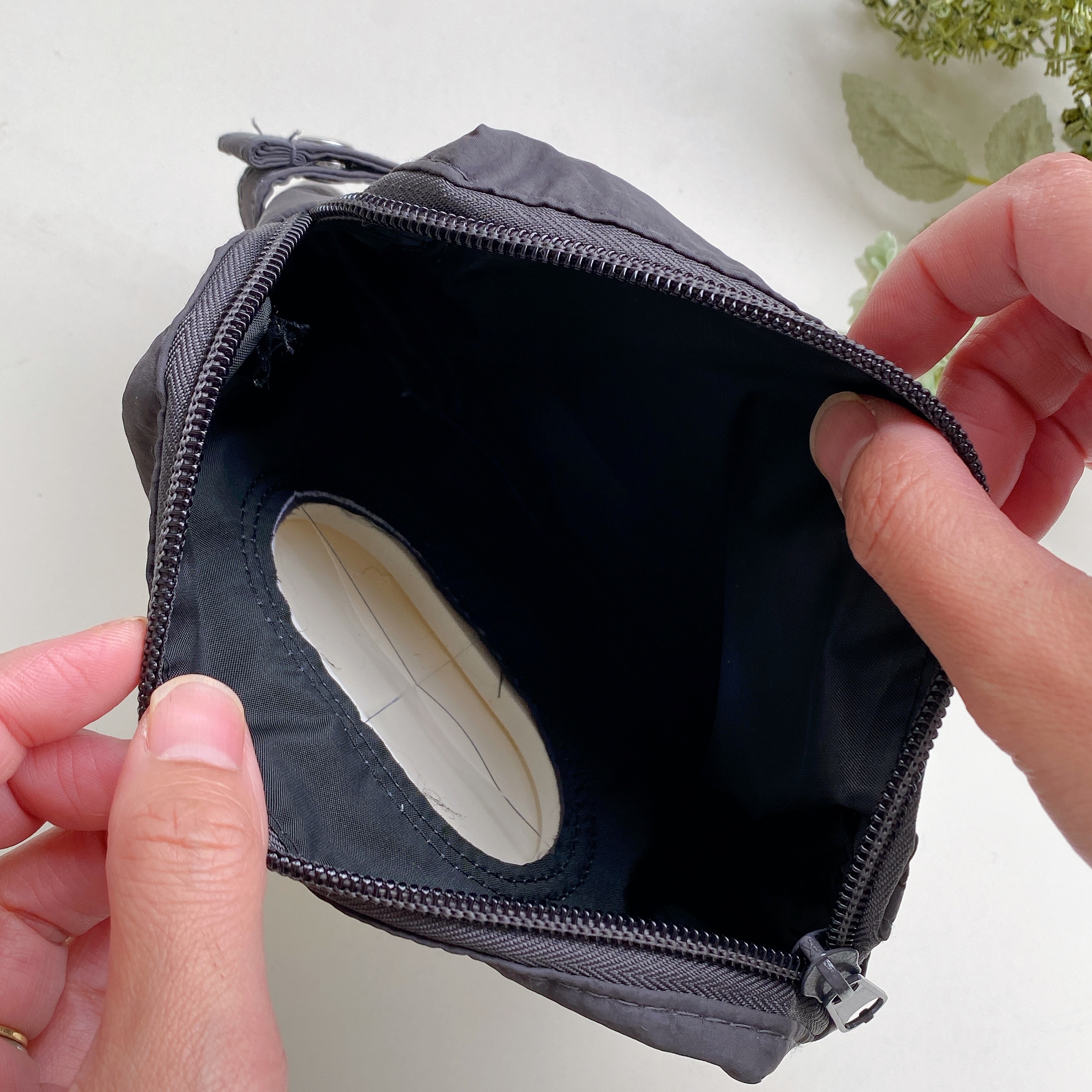 開いた黒いポーチを手に持ち、中の大きな収納スペースが見えています。