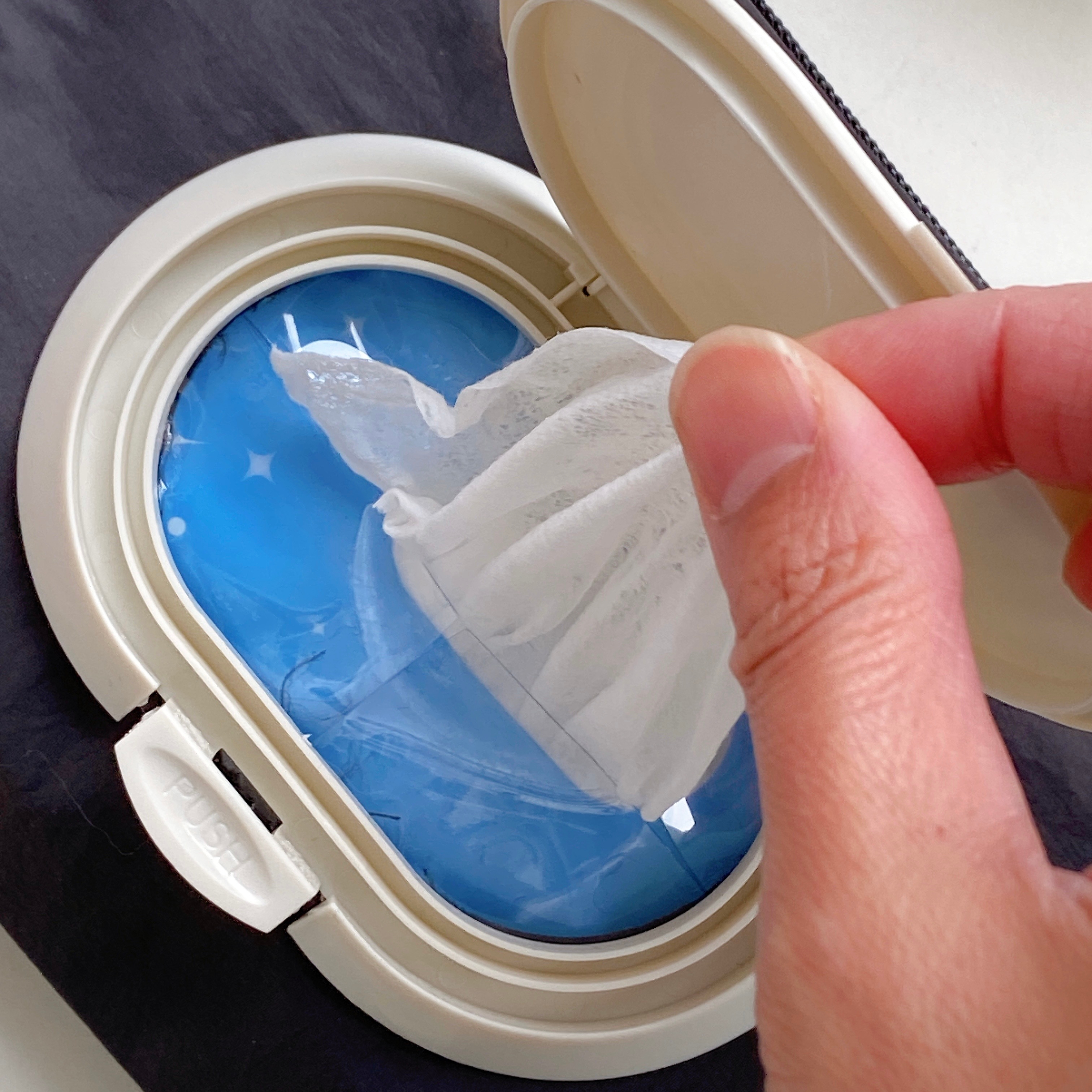 手がウェットティッシュをケースから取り出す瞬間を捉えた写真。