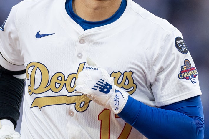野球選手がユニフォームを着て試合中に走っている。背景に観客が見える。