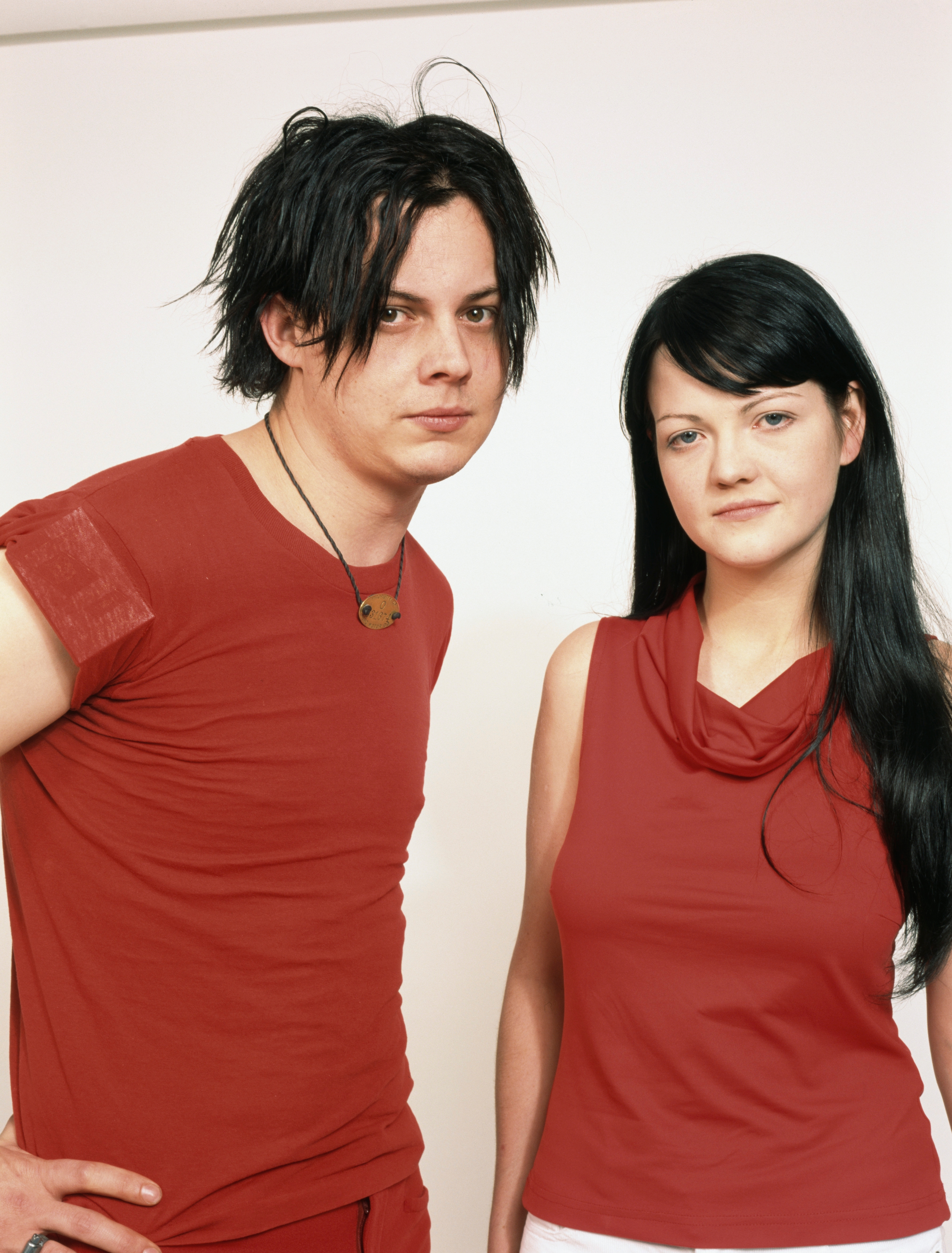 Two people with casual hairstyles and red attire stand facing forward