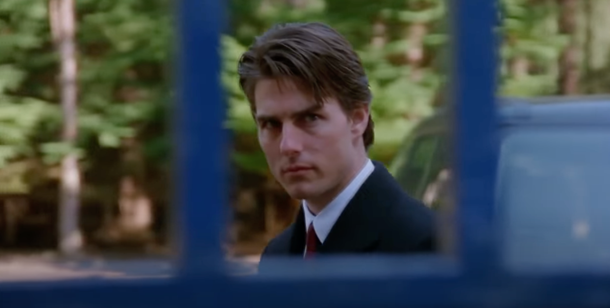Tom Cruise in a scene from &quot;Eyes Wide Shut,&quot; seen through a tall iron gate wearing a serious expression