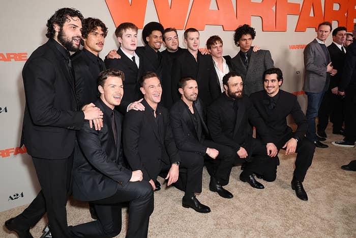 Group of men in suits posing together on a carpet at a celebrity event