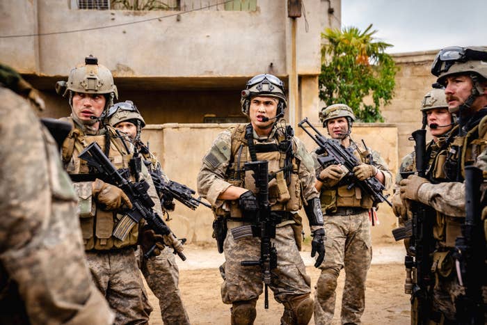 A group of soldiers in tactical gear standing together, armed and alert in an urban environment
