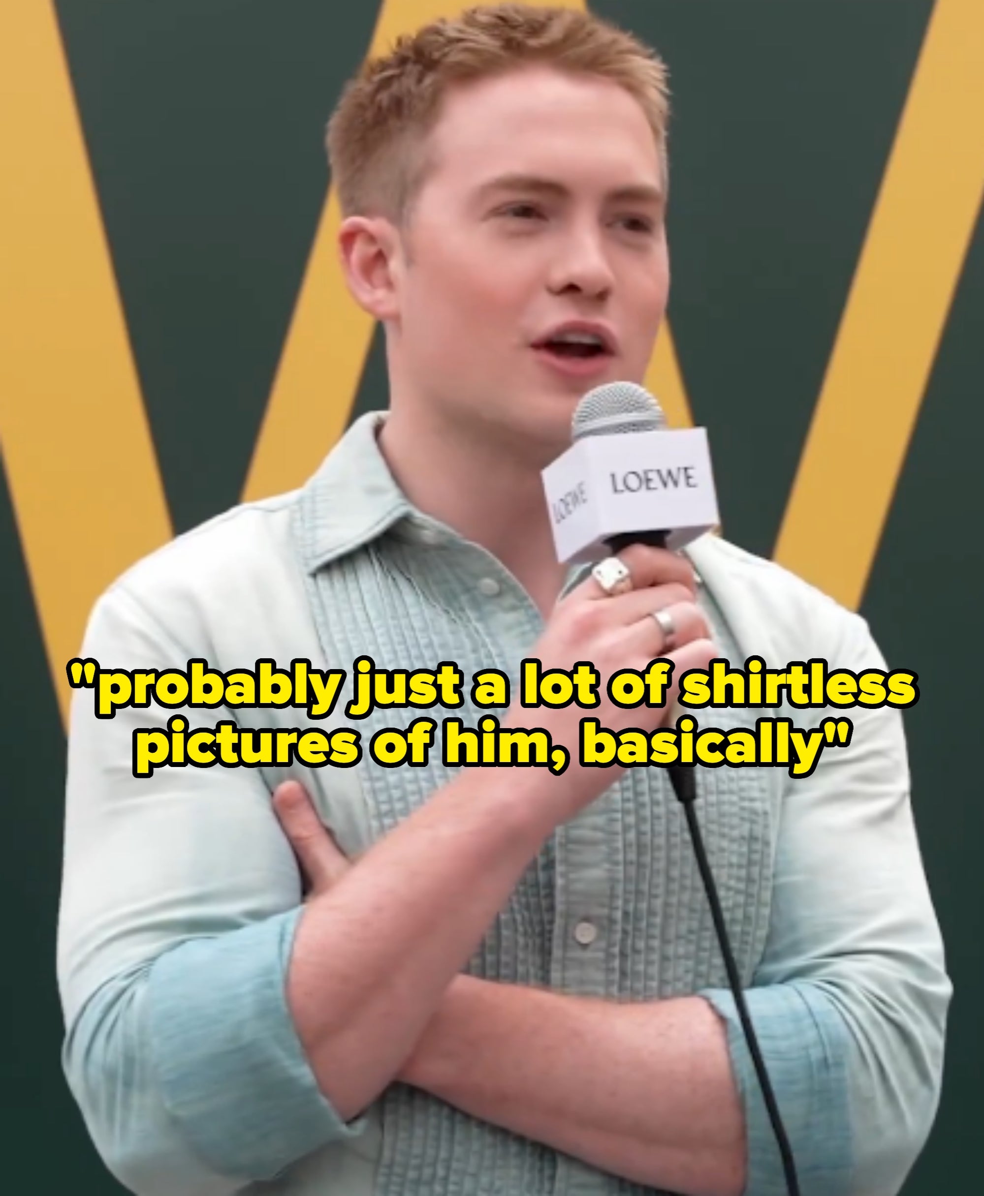 Person speaking into a microphone at a Loewe event, wearing a light textured shirt, short sleeve rolled up