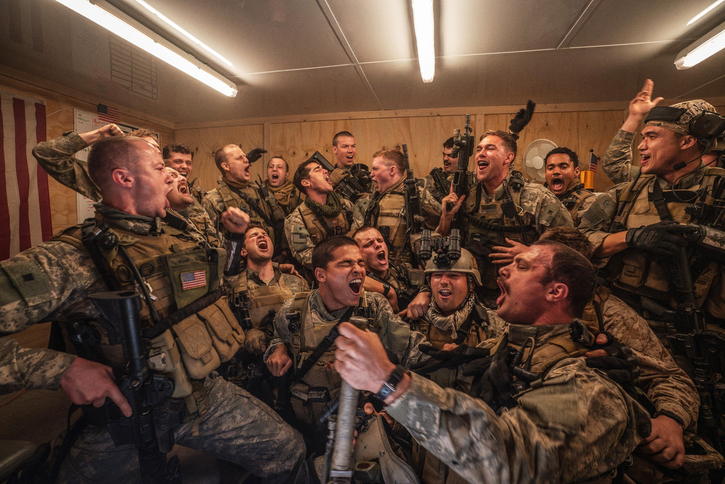 Group of soldiers in uniform exuberantly celebrating inside a room, displaying camaraderie and joy