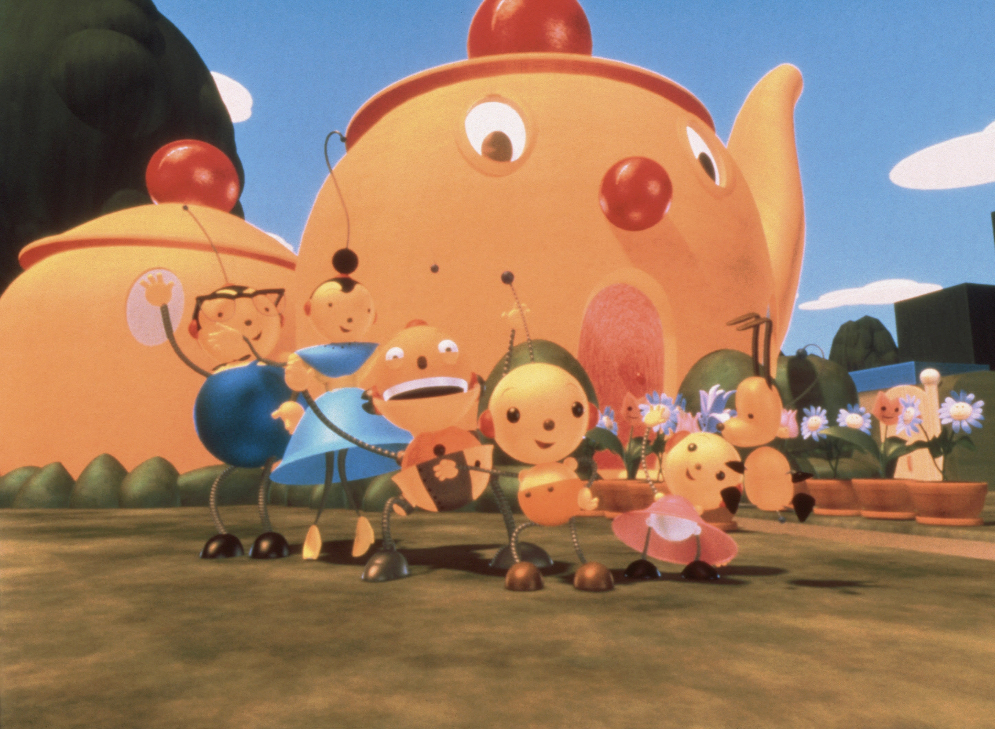 Animated characters stand in front of whimsical teapot-shaped houses, with one character holding a guitar