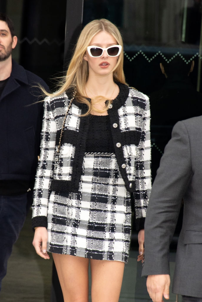 celebrity drama Individual in a trendy plaid skirt match with black trim and white sunglasses, strolling outdoors