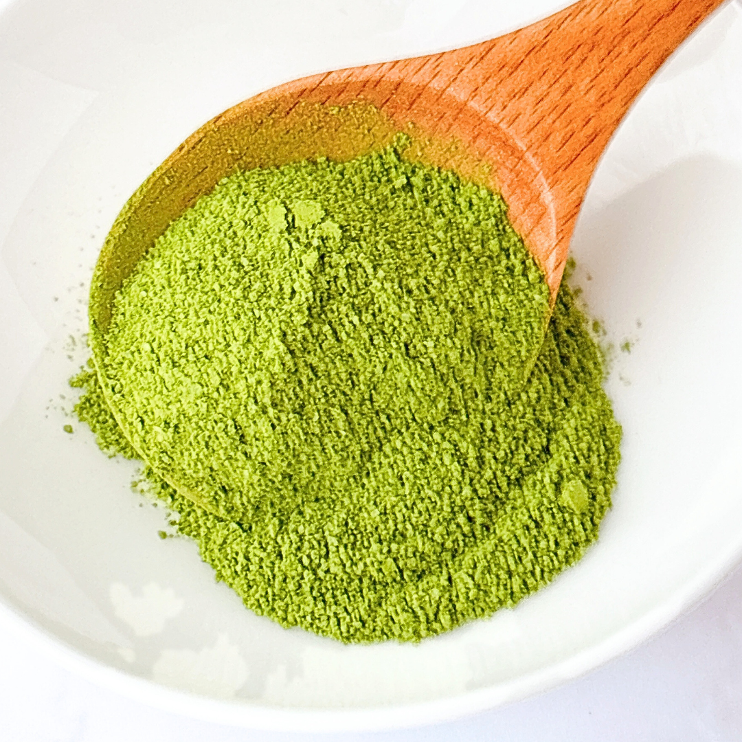 白い皿に盛られた緑茶パウダーの上に木製のスプーン。