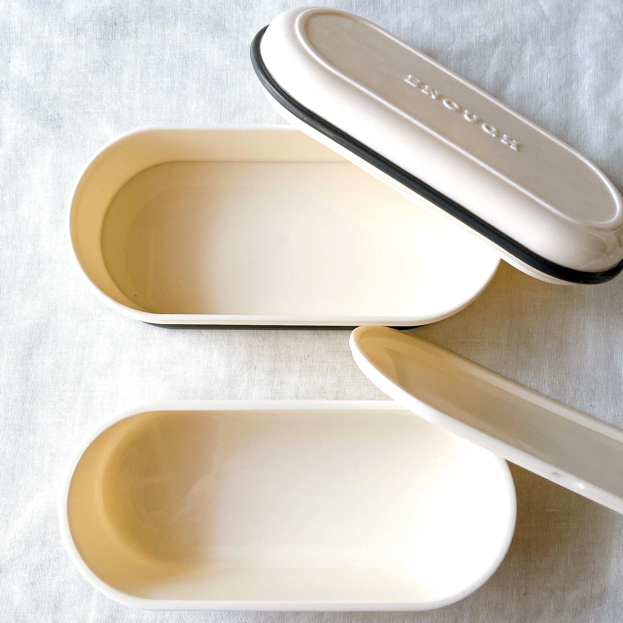 開いた楕円形のフタ付き容器が2つ、布の上に並んでいる。