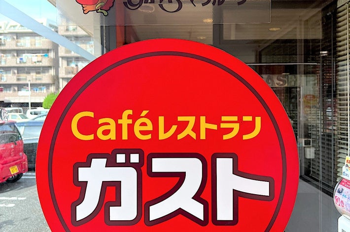 Sign for Café Restaurant Gasto in a storefront window. Bright red circle with white and yellow text