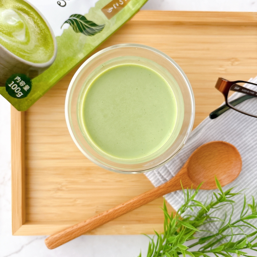 眼鏡と木製スプーンが添えられたトレーの上に置かれた緑色の飲み物。