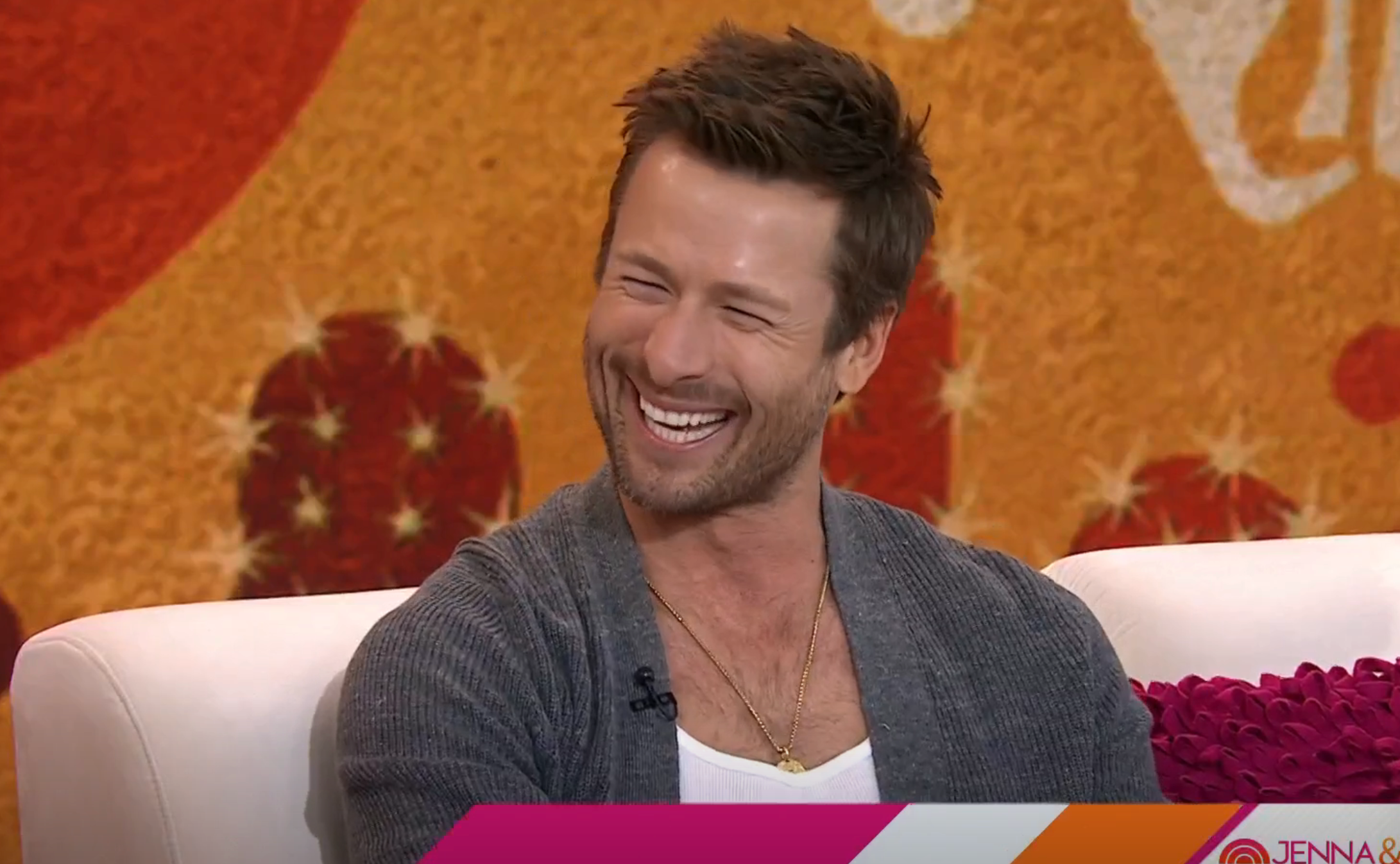 Glen Powell laughing on a talk show