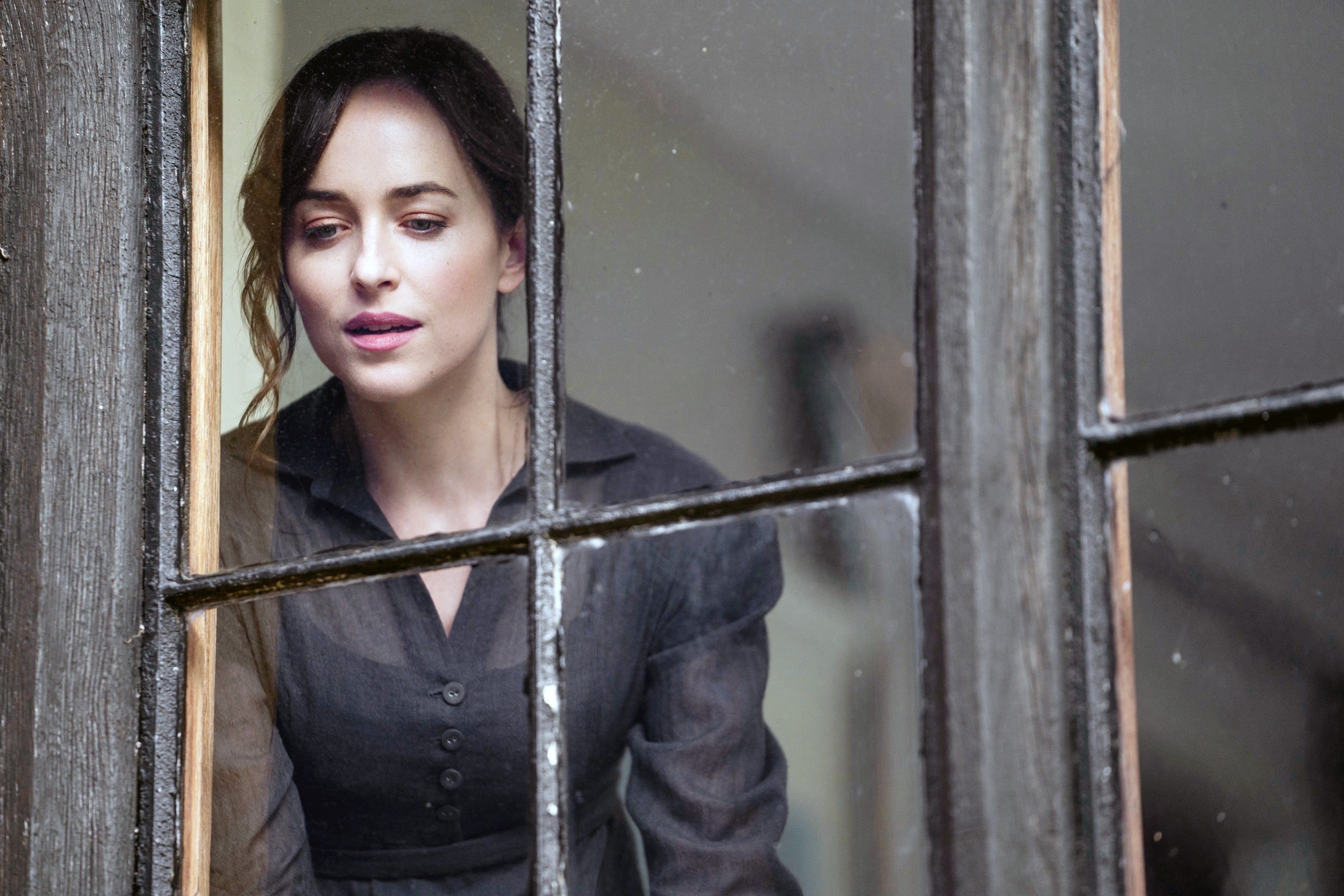 Dakota Johnson as Anne Elliot in "Persuasion" looking out of a window