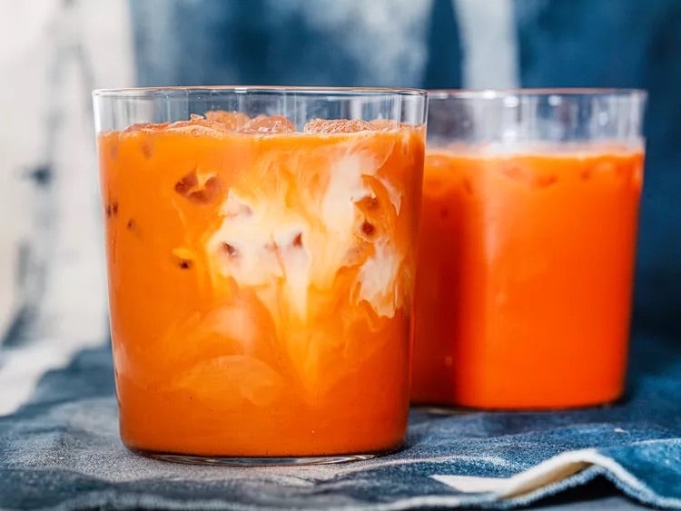 Two glasses of iced Thai tea with creamy swirls on top