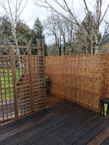 Wooden platform with privateness screens made of lattice and bamboo, overlooking trees and a grassy area